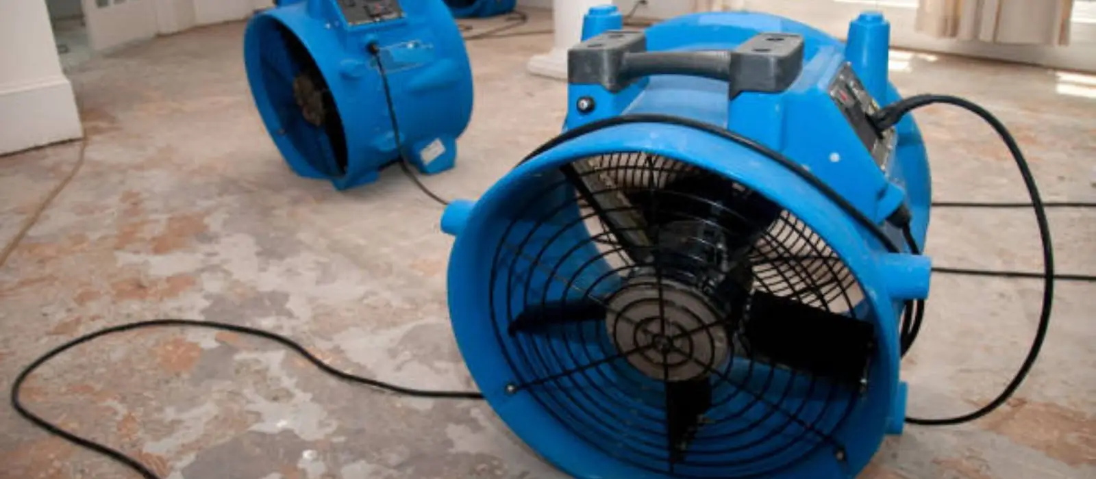 Blue air movers drying a water damaged room