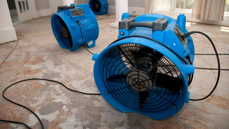 Blue air mover drying a basement floor after flooding